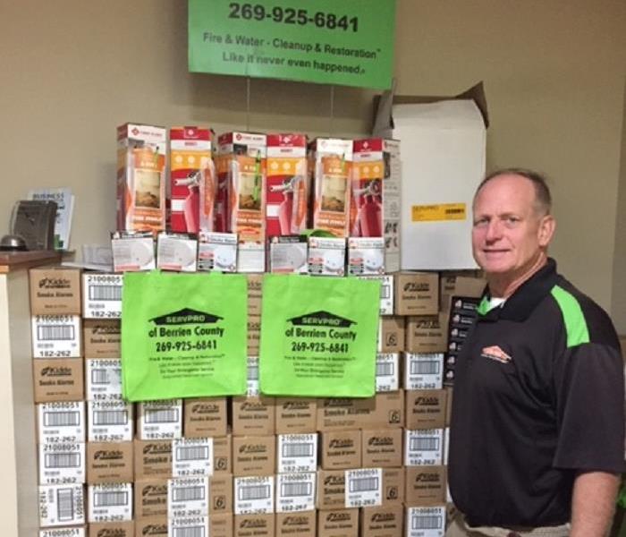 male employee standing in front of boxes of smoke alarms
