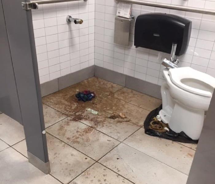 broken toilet in stall with sewage on tile floor